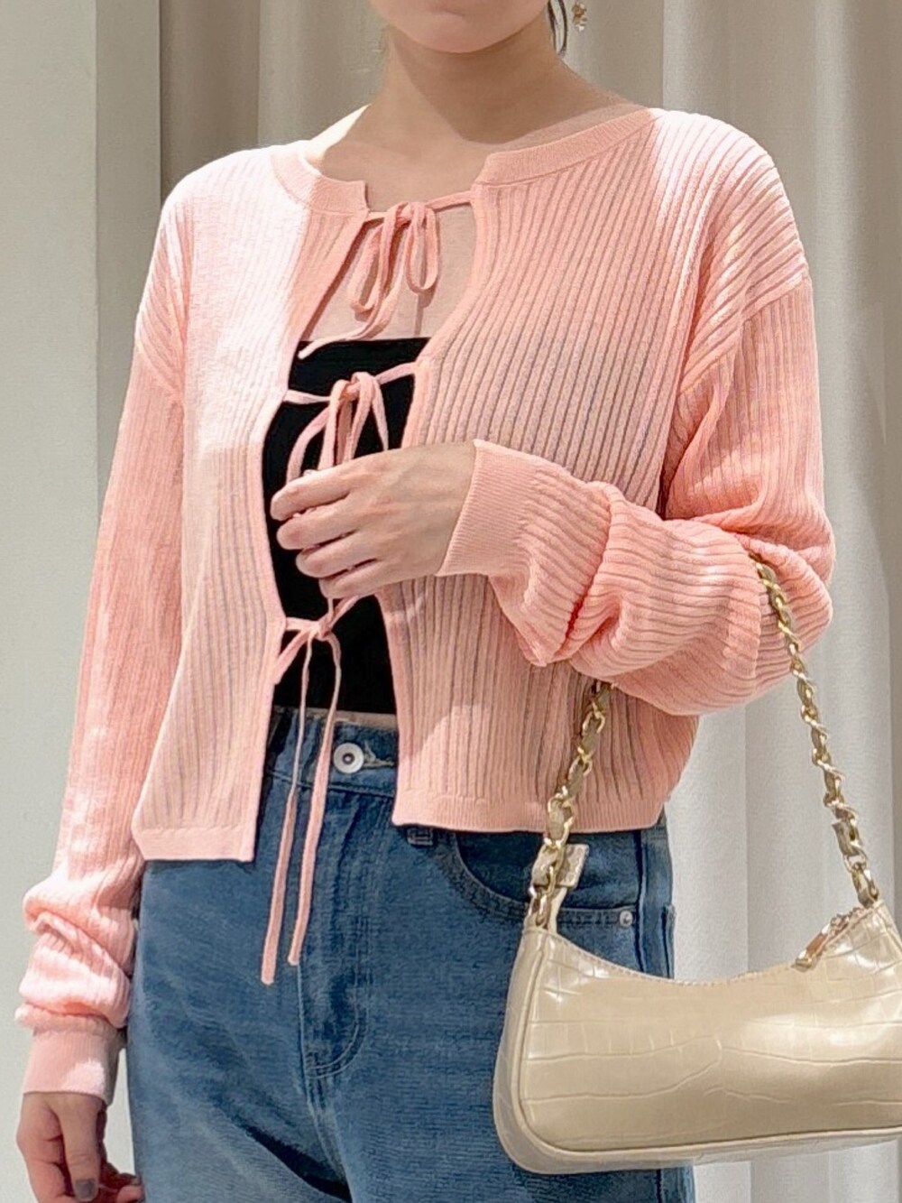 ピンク系のカーディガン/ボレロ、ブラック系のキャミソール、ブルー系のデニムパンツを着用したレディースの秋コーディネートの2枚目の写真