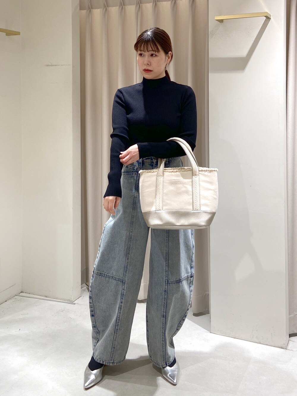 ブラック系のニット/セーター、シルバー系のトートバッグ、ブルー系のデニムパンツを着用したレディースの冬コーディネートの4枚目の写真