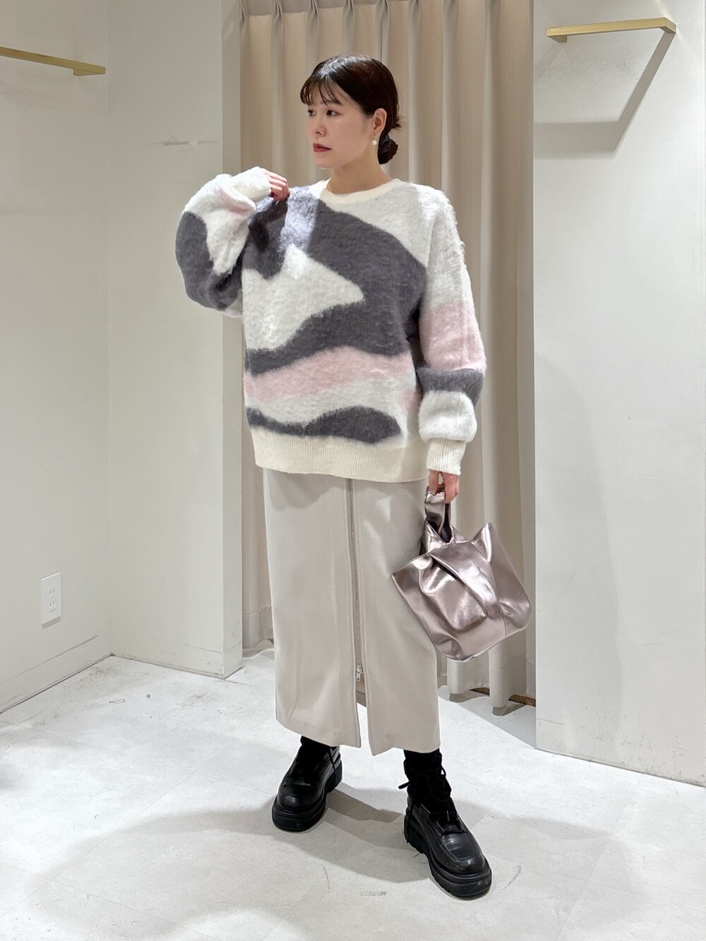 ホワイト系のニット/セーター、グレー系のスカート、シルバー系のハンドバッグを着用したレディースの冬コーディネートの2枚目の写真