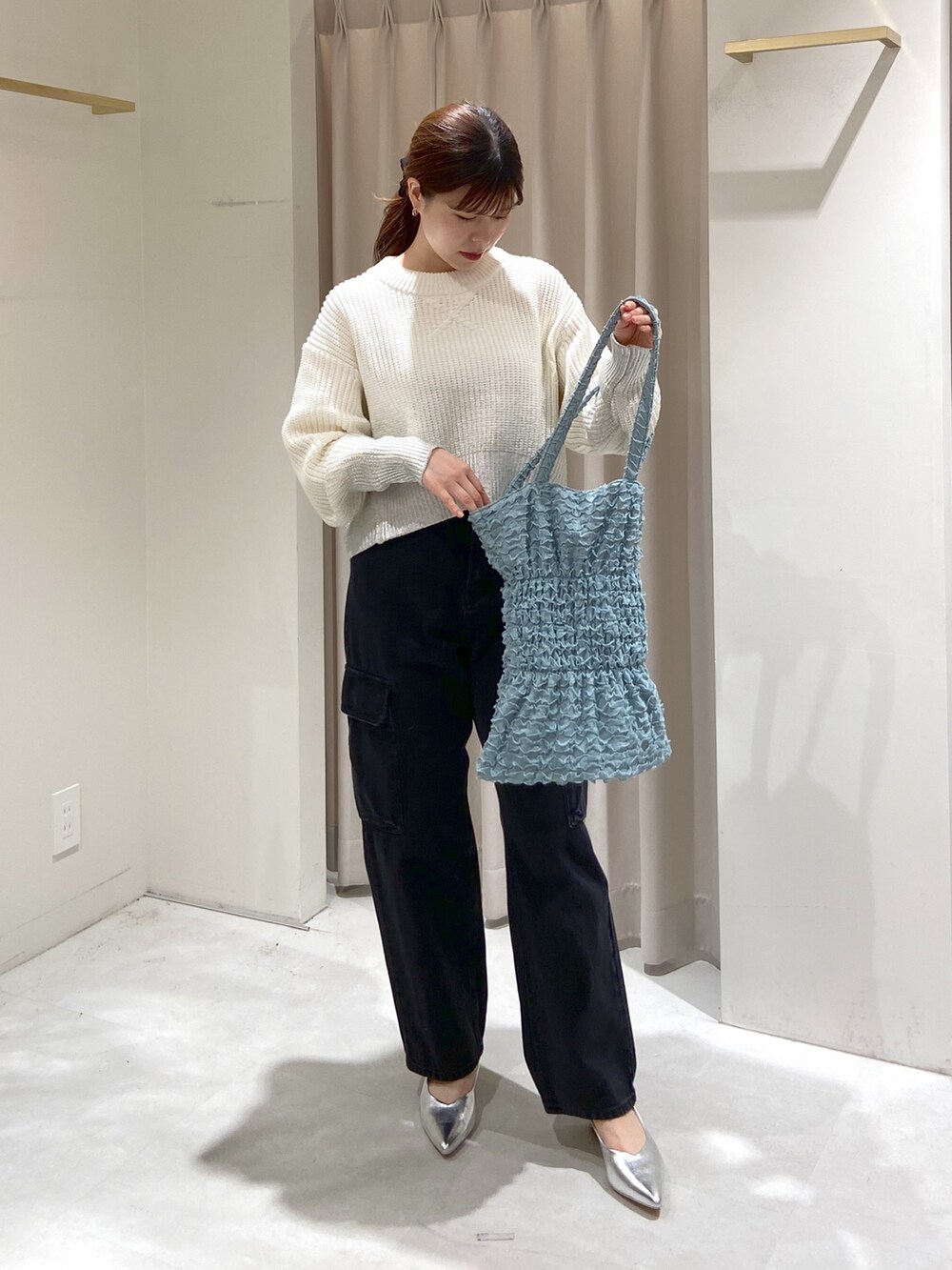 ホワイト系のニット/セーター、グリーン系のトートバッグ、ブラック系のデニムパンツを着用したレディースの冬コーディネートの2枚目の写真