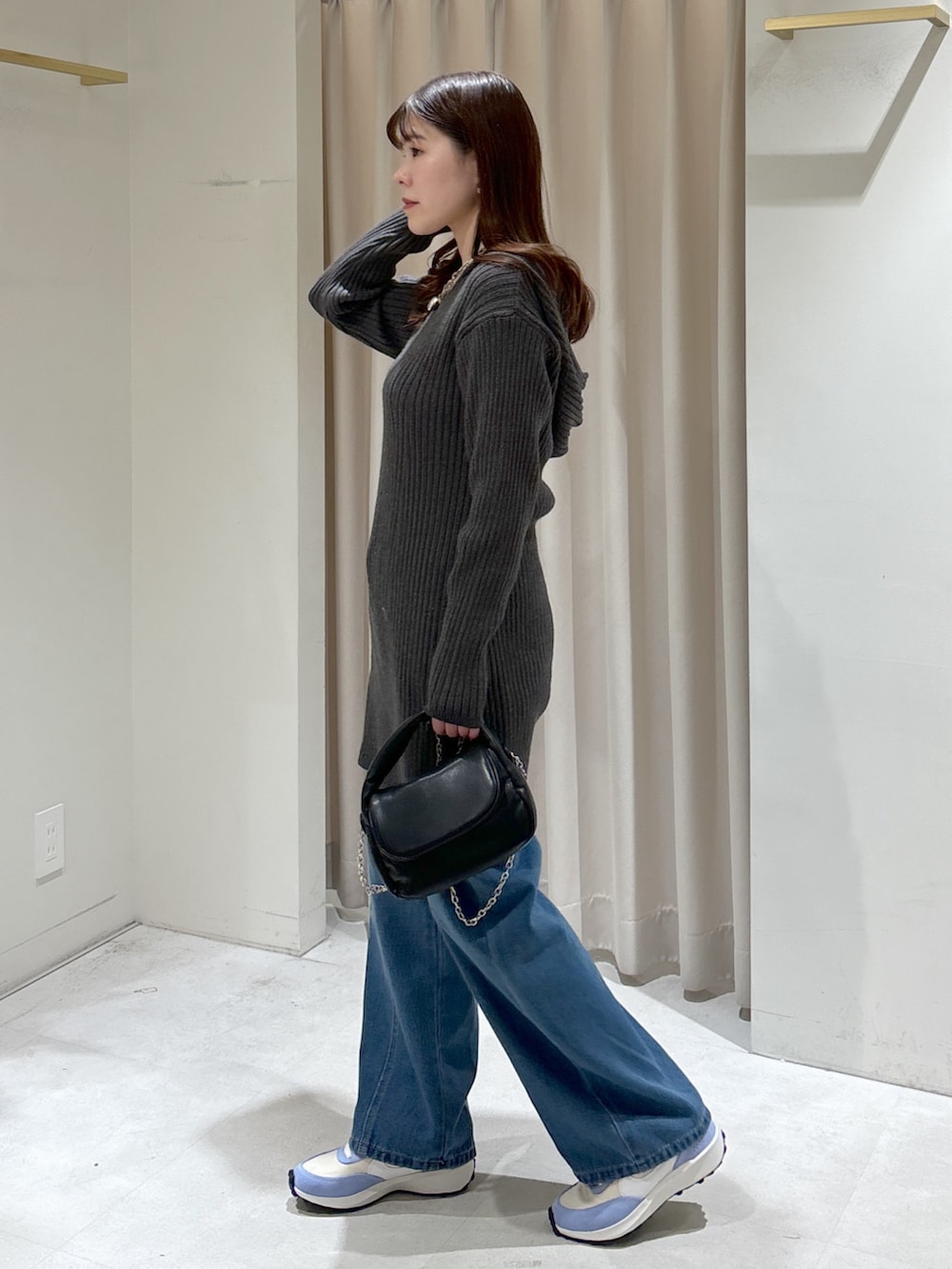 グレー系のワンピース、ブラック系のショルダーバッグ、ブルー系のデニムパンツを着用したレディースの冬コーディネートの3枚目の写真