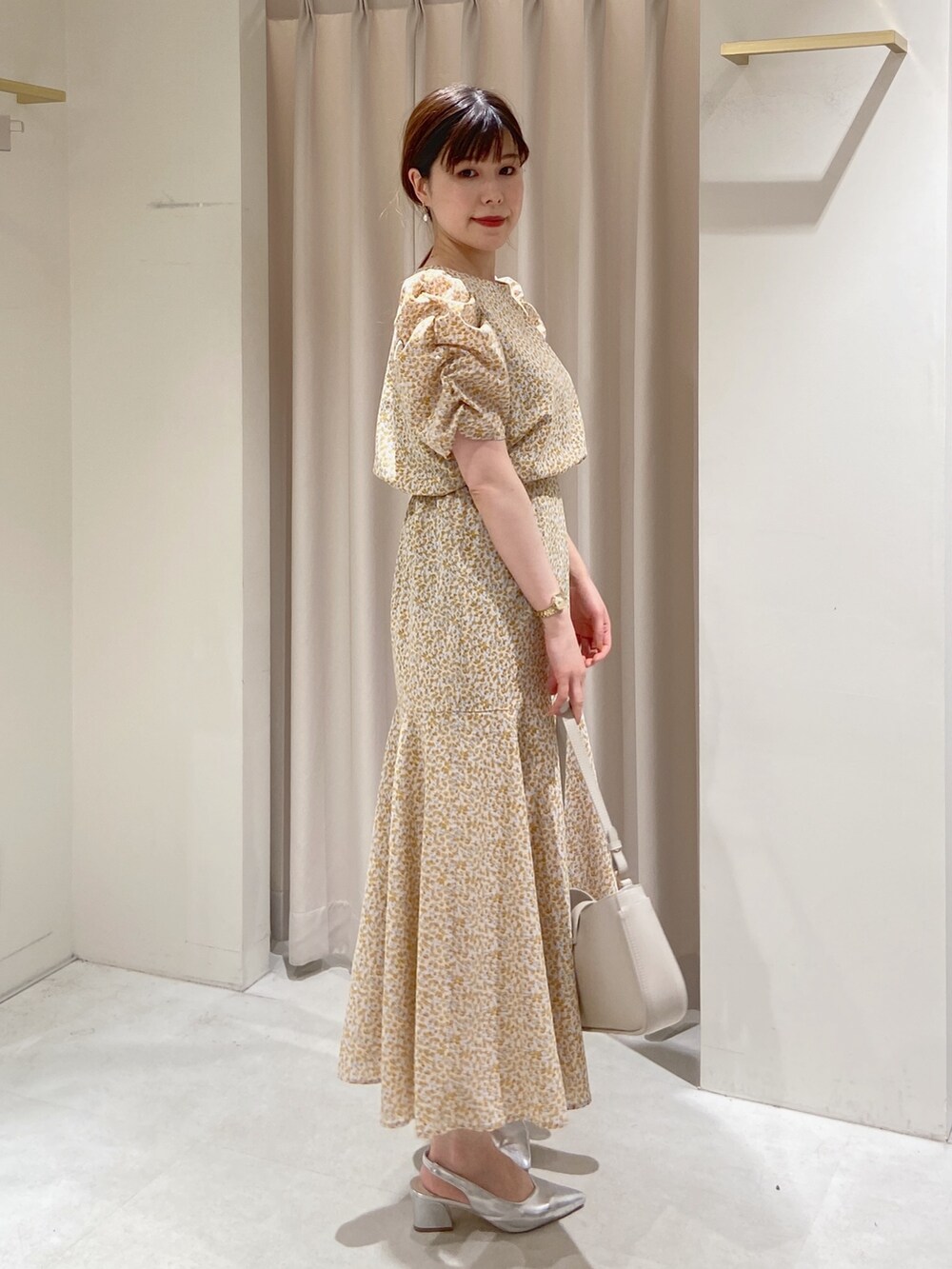 イエロー系のワンピース、グレー系のショルダーバッグ、シルバー系のパンプスを着用したレディースの春コーディネートの2枚目の写真