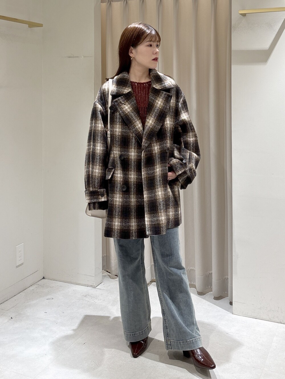 レッド系のニット/セーター、ブラウン系のトートバッグ、ブルー系のデニムパンツを着用したレディースの秋コーディネートの9枚目の写真