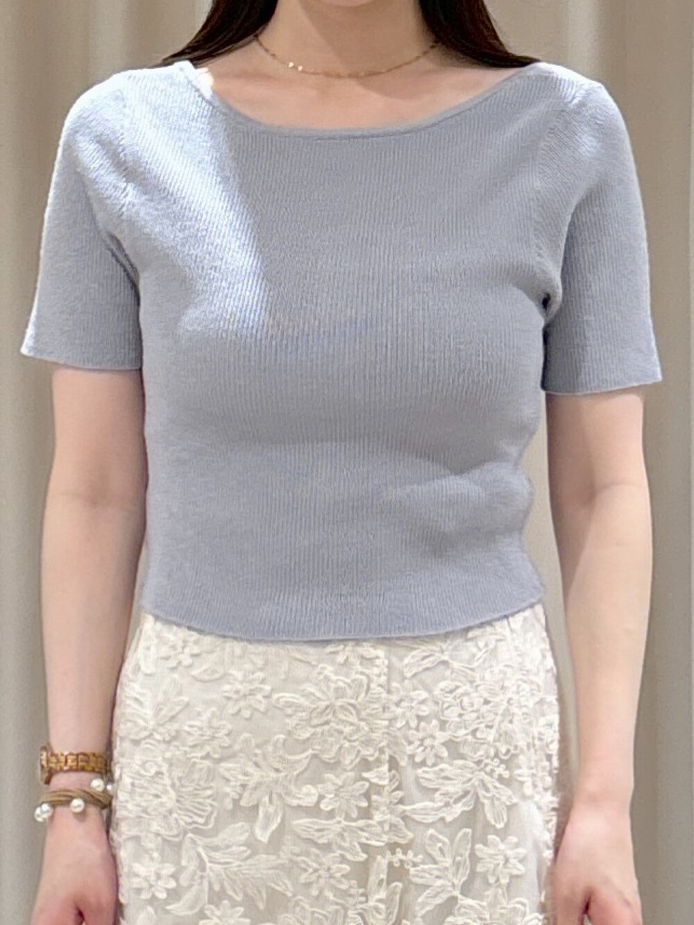 グレー系のニット/セーター、ホワイト系のスカート、ホワイト系のボストンバッグを着用したレディースの夏コーディネートの4枚目の写真