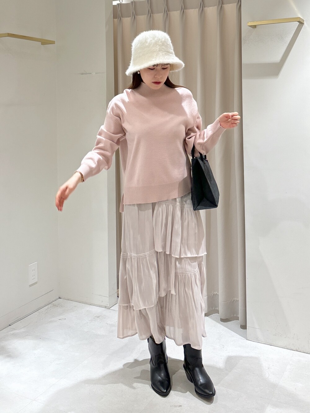 ブラック系のトートバッグ、ホワイト系のスカート、ブラック系のブーツを着用したレディースの冬コーディネートの2枚目の写真