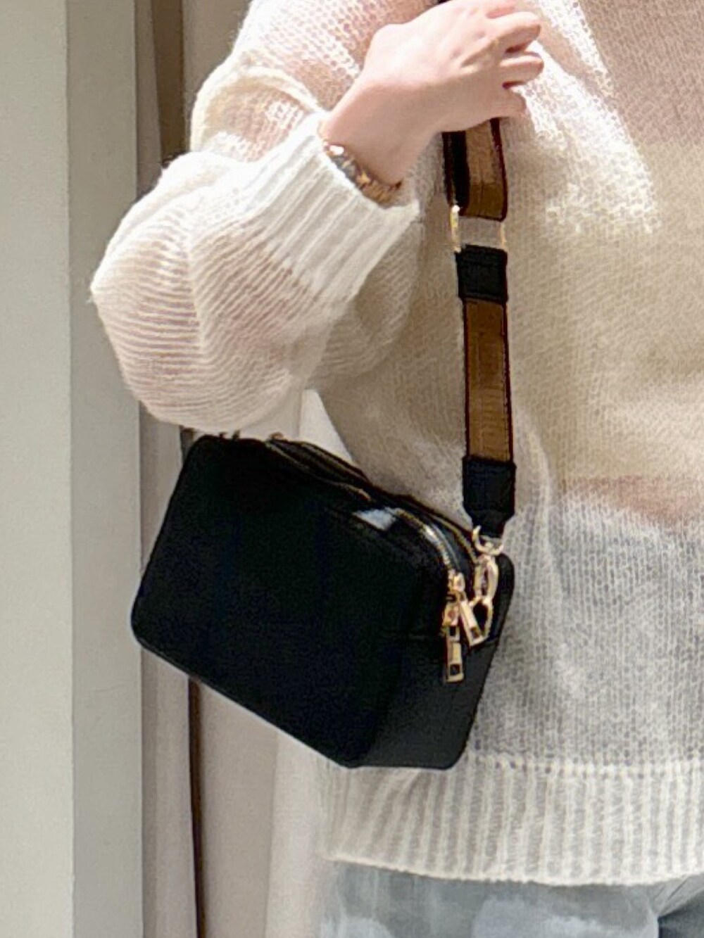 ホワイト系のニット/セーター、ブラック系のショルダーバッグ、ブルー系のデニムパンツを着用したレディースの冬コーディネートの4枚目の写真