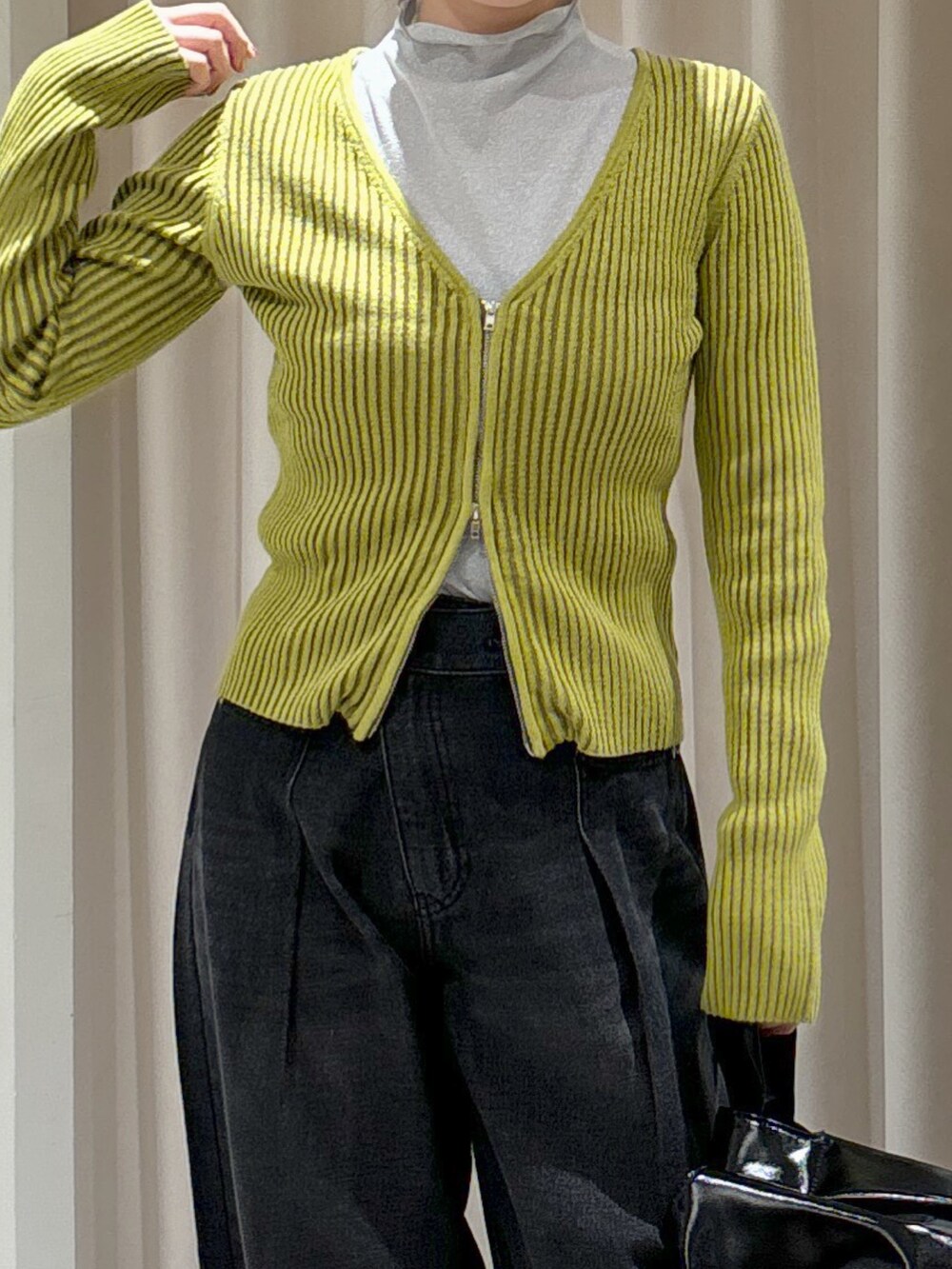 グリーン系のニット/セーター、グレー系のTシャツ/カットソー、ブラック系のハンドバッグを着用したレディースの秋コーディネートの2枚目の写真