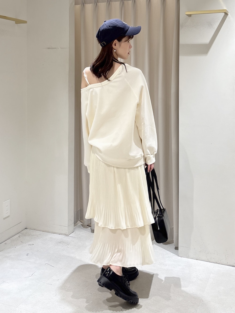 ホワイト系のスウェット、ホワイト系のスカート、ブラック系のショルダーバッグを着用したレディースの春コーディネートの5枚目の写真