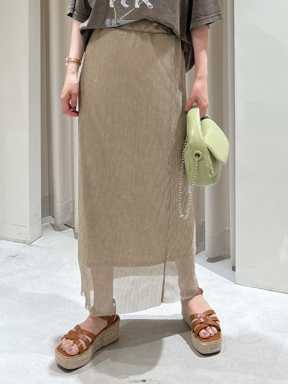 ブラウン系のTシャツ/カットソー、ゴールド系のスカート、グリーン系のショルダーバッグを着用したレディースの夏コーディネートの6枚目の写真