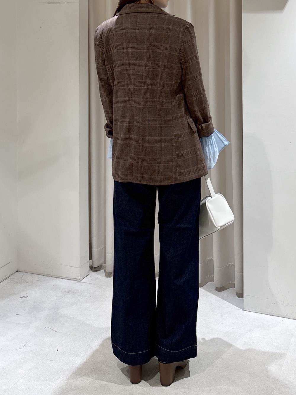 ブラウン系のテーラードジャケット、ホワイト系のハンドバッグ、ブルー系のデニムパンツを着用したレディースの春コーディネートの4枚目の写真