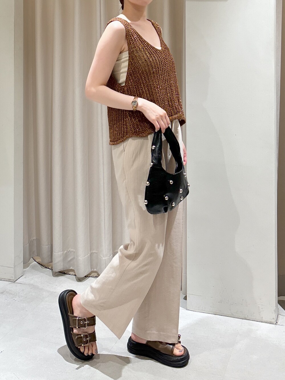 ブラウン系のベスト、ホワイト系のキャミソール、ブラック系のハンドバッグを着用したレディースの夏コーディネートの3枚目の写真