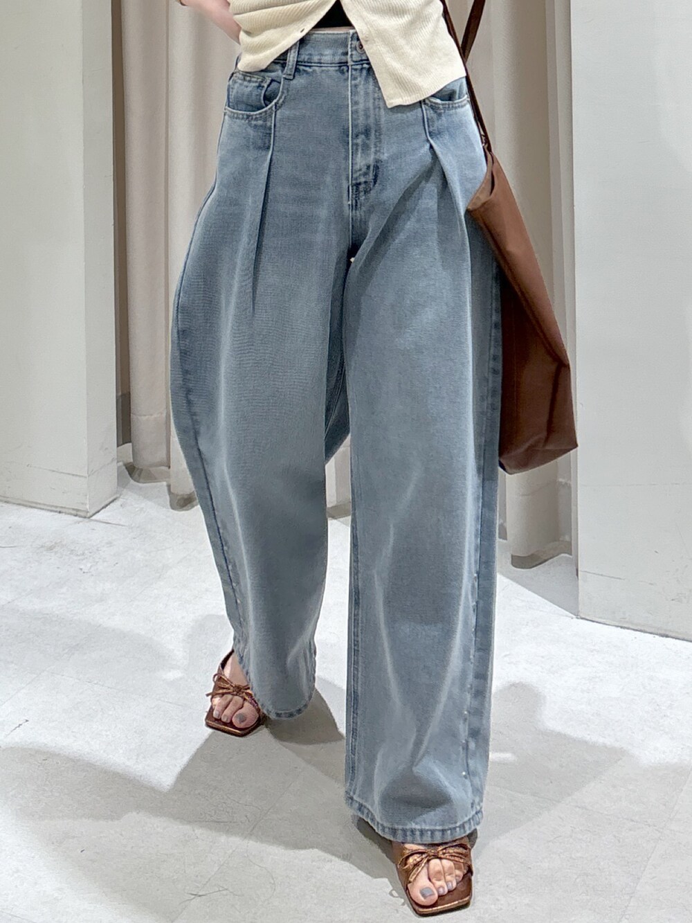 ブルー系のデニムパンツ、ブラウン系のサンダル、ブラック系のキャミソールを着用したレディースの春コーディネートの6枚目の写真