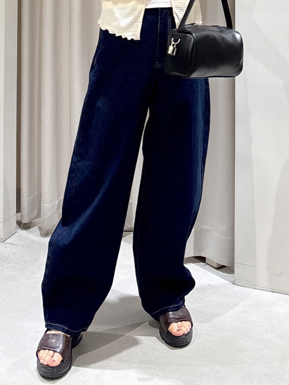 ブルー系のデニムパンツ、ブラック系のハンドバッグ、ブラウン系のサンダルを着用したレディースの夏コーディネートの6枚目の写真