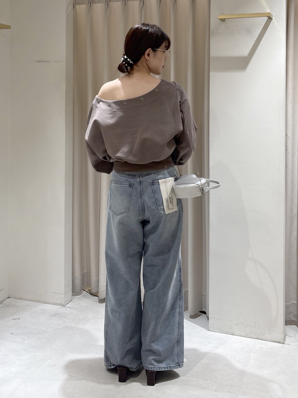 ブラウン系のスウェット、ブルー系のデニムパンツ、シルバー系のショルダーバッグを着用したレディースの冬コーディネートの5枚目の写真