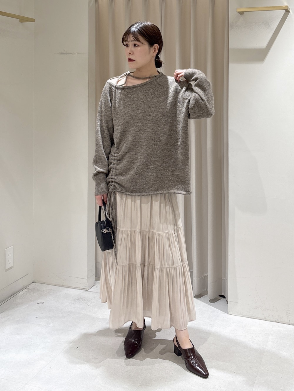 ブラウン系のニット/セーター、ホワイト系のスカート、ブラウン系のパンプスを着用したレディースの冬コーディネートの2枚目の写真
