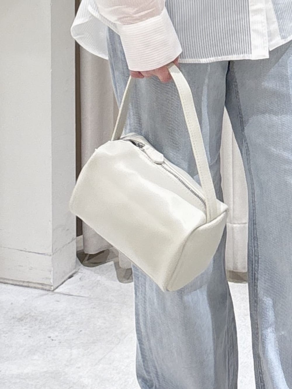 ホワイト系のシャツ/ブラウス、ブラック系のニット/セーター、ブルー系のデニムパンツを着用したレディースの春コーディネートの5枚目の写真