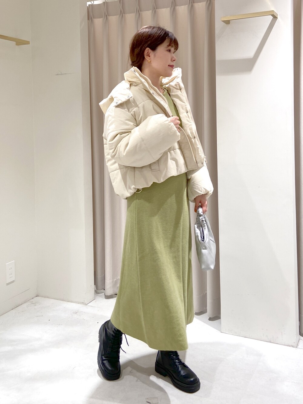 ホワイト系のブルゾン、グリーン系のワンピース、シルバー系のショルダーバッグを着用したレディースの秋コーディネートの3枚目の写真