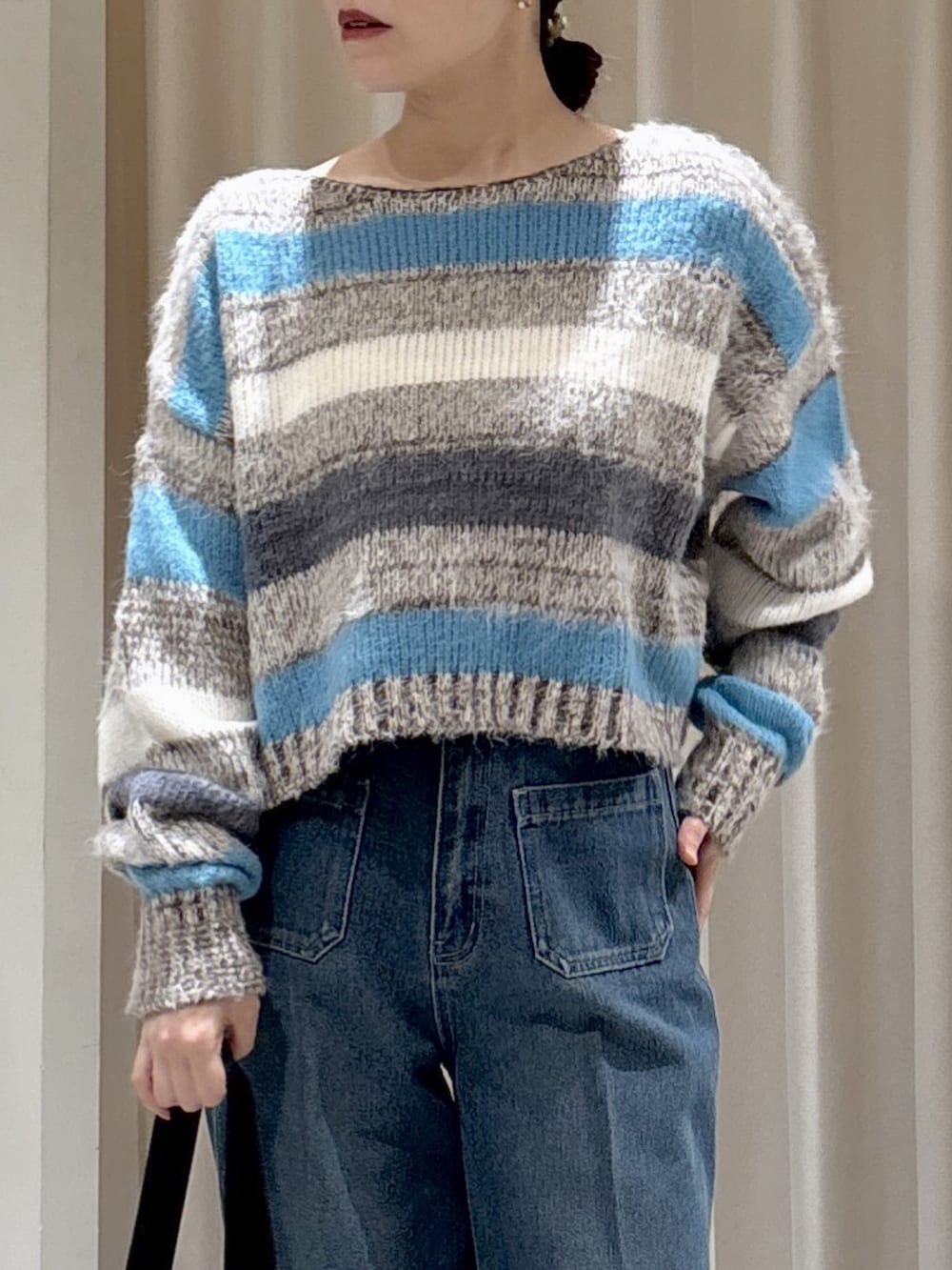 グレー系のニット/セーター、ブラック系のショルダーバッグ、ブルー系のデニムパンツを着用したレディースの秋コーディネートの3枚目の写真