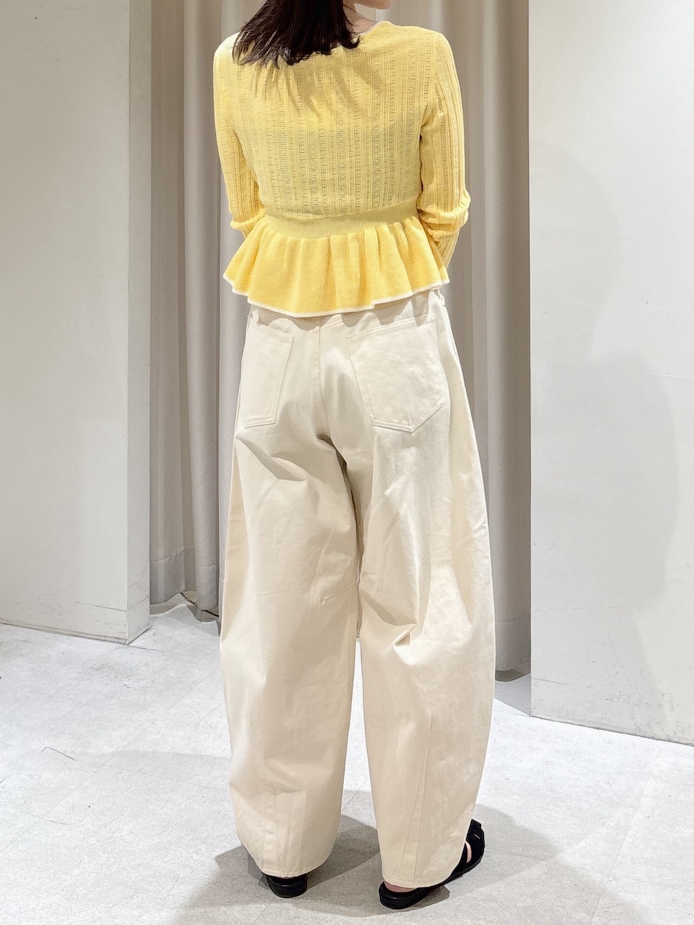 イエロー系のニット/セーター、ホワイト系のその他パンツ、ブラウン系のハンドバッグを着用したレディースの春コーディネートの4枚目の写真