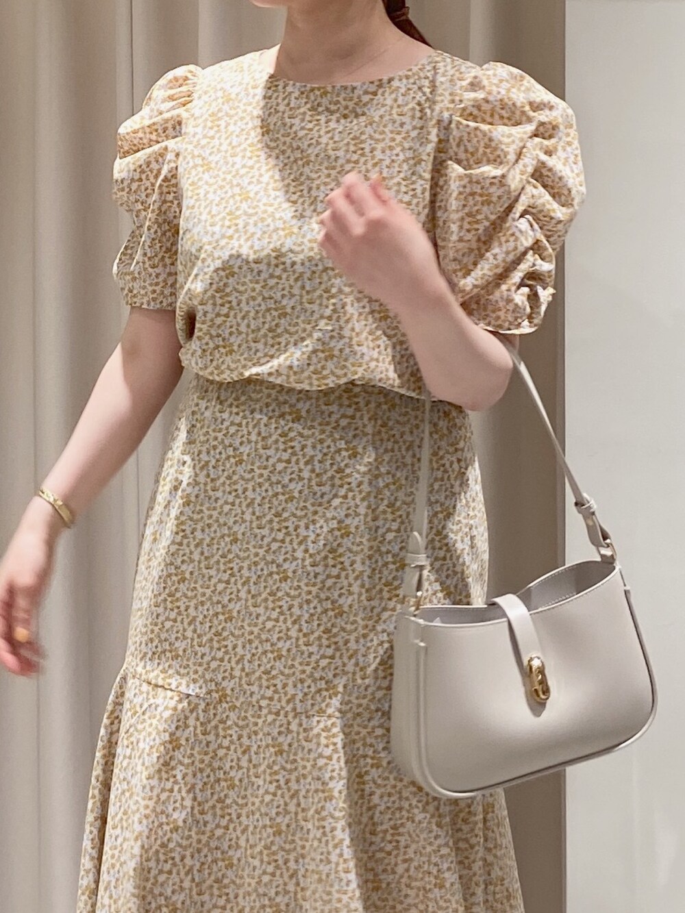 イエロー系のワンピース、グレー系のショルダーバッグ、シルバー系のパンプスを着用したレディースの春コーディネートの5枚目の写真