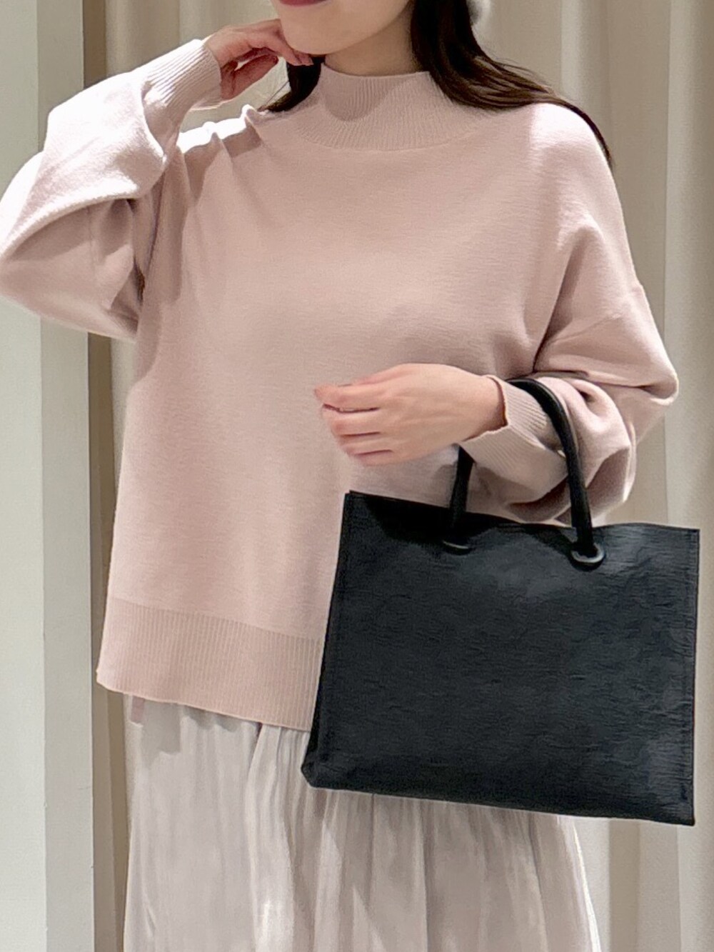 ブラック系のトートバッグ、ホワイト系のスカート、ブラック系のブーツを着用したレディースの冬コーディネートの3枚目の写真