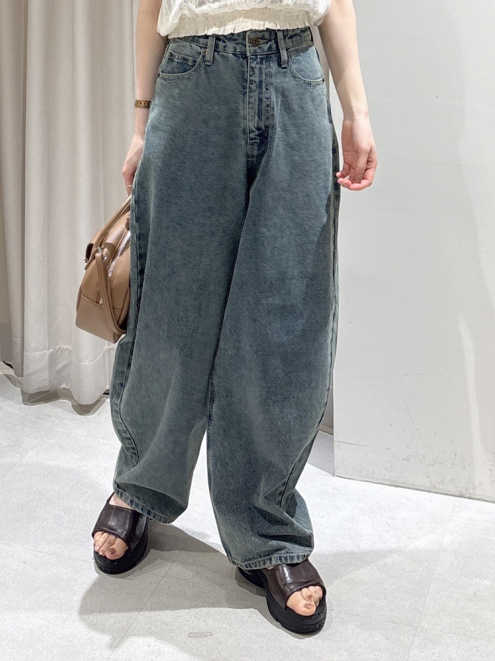 ホワイト系のシャツ/ブラウス、ブラウン系のハンドバッグ、ブルー系のデニムパンツを着用したレディースの夏コーディネートの2枚目の写真