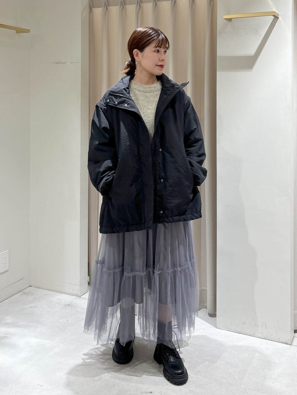 ブラック系のダウンジャケット/コート、グレー系のスカート、ブラック系のブーツを着用したレディースの秋コーディネートの2枚目の写真