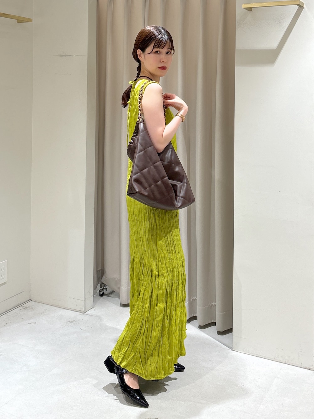 グリーン系のワンピース、ブラウン系のトートバッグ、ブラック系のデニムパンツを着用したレディースの秋コーディネートの2枚目の写真