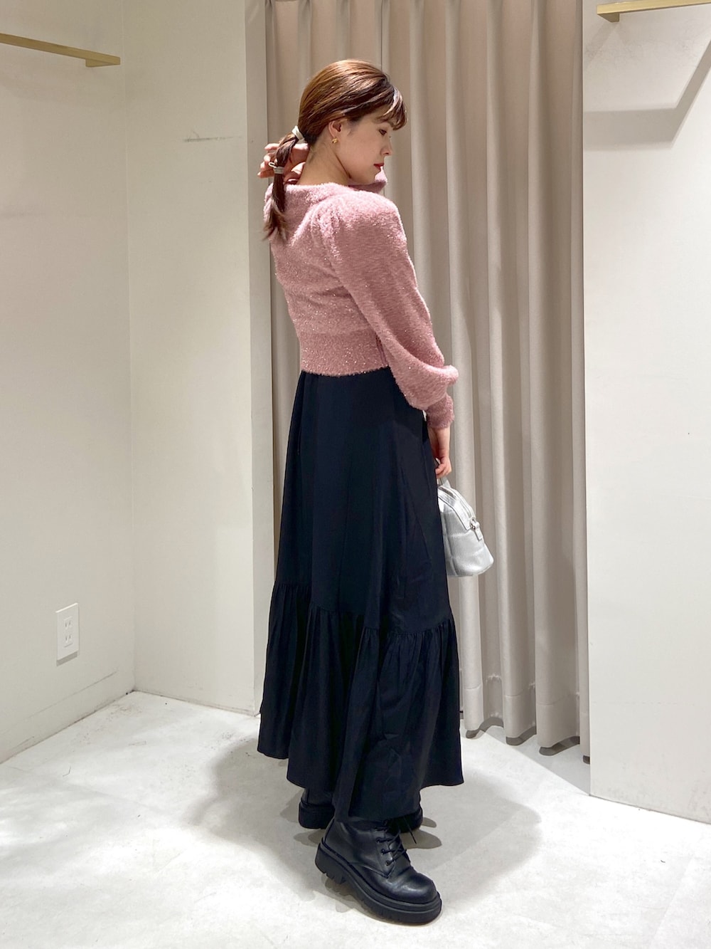 ピンク系のニット/セーター、ブラック系のワンピース、シルバー系のショルダーバッグを着用したレディースの冬コーディネートの2枚目の写真