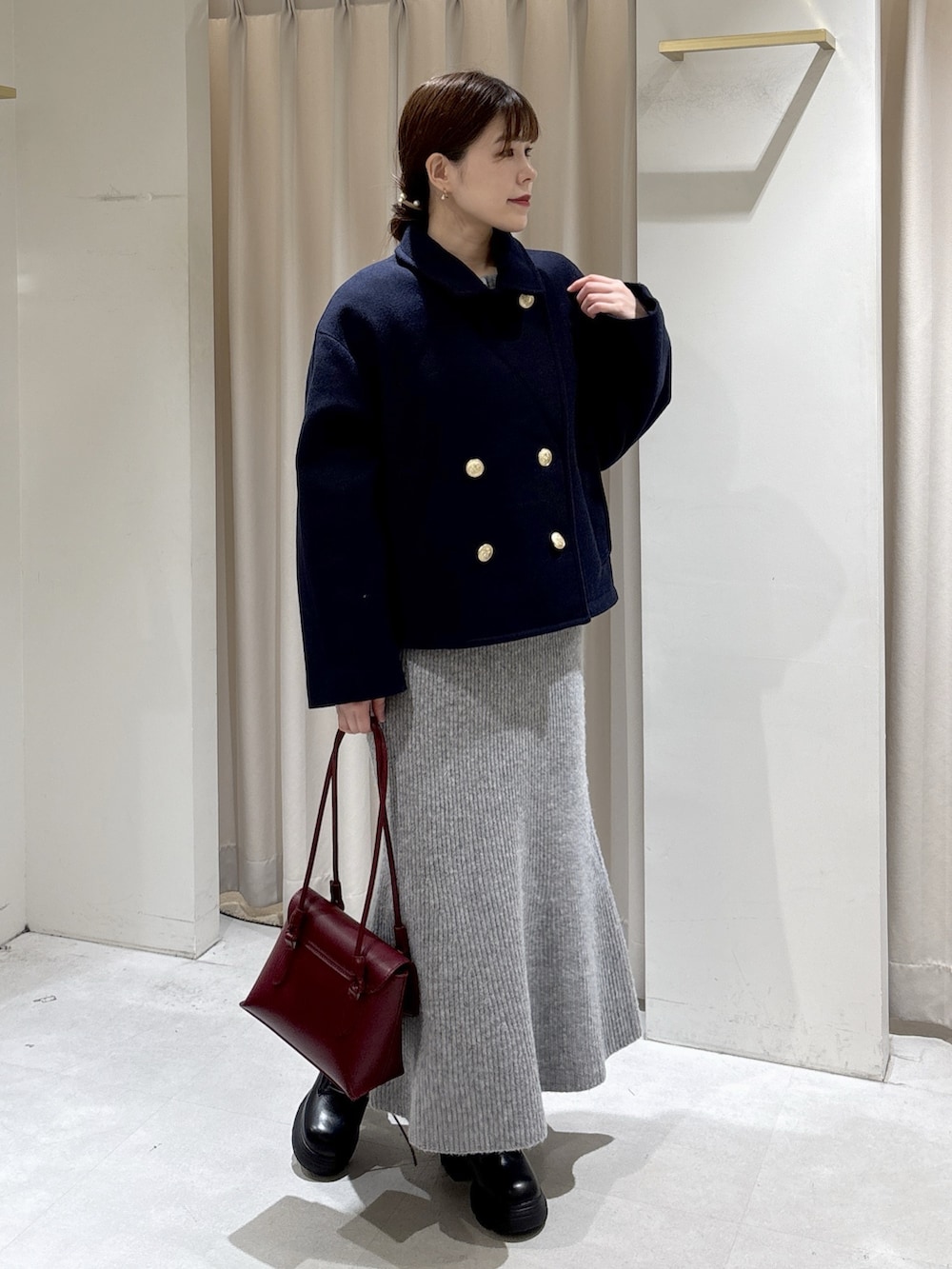 グレー系のワンピース、レッド系のショルダーバッグ、ブラック系のブーツを着用したレディースの秋コーディネートの6枚目の写真