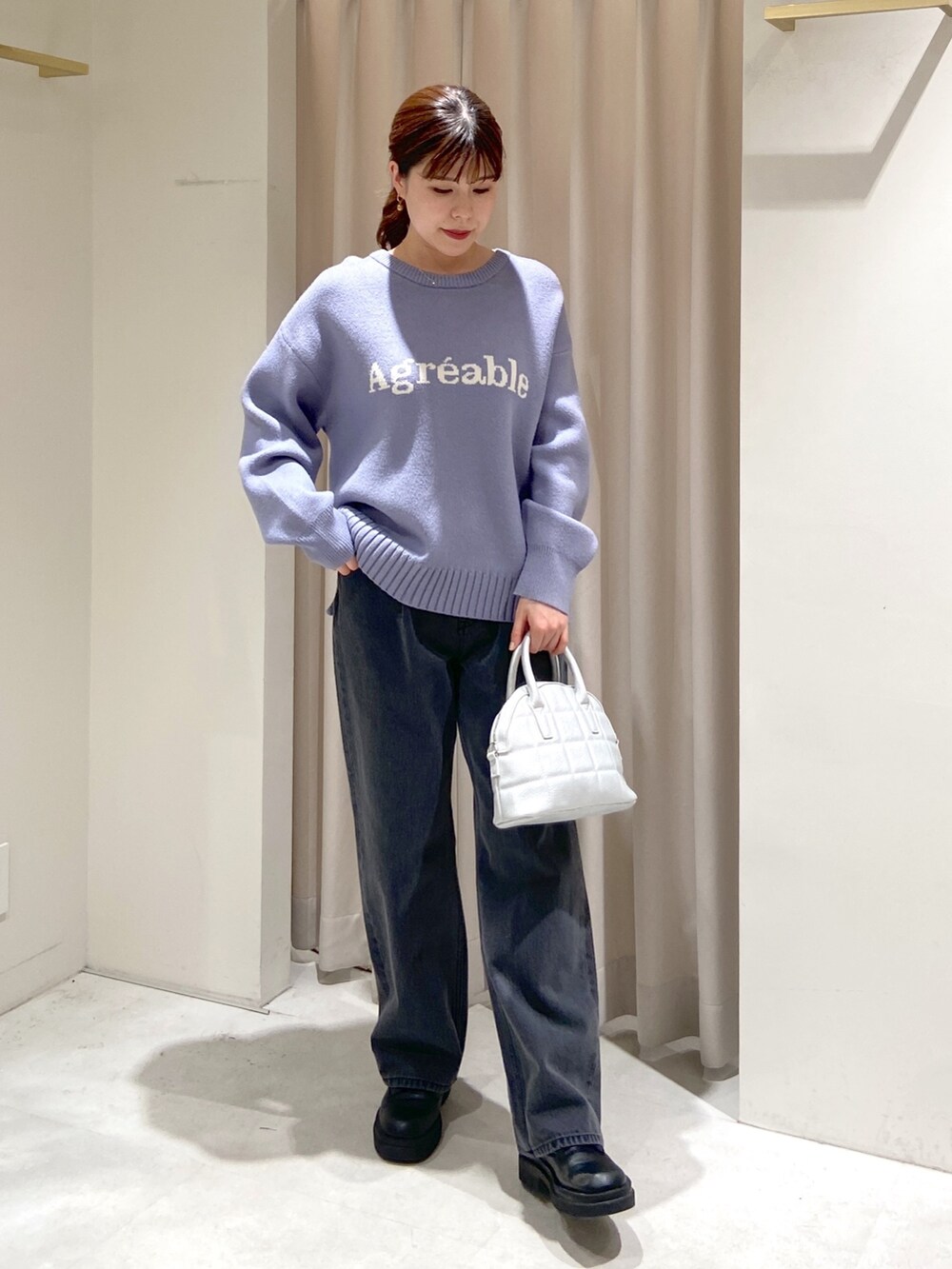 シルバー系のショルダーバッグ、ブラック系のデニムパンツ、ブラック系のブーツを着用したレディースの冬コーディネートの2枚目の写真