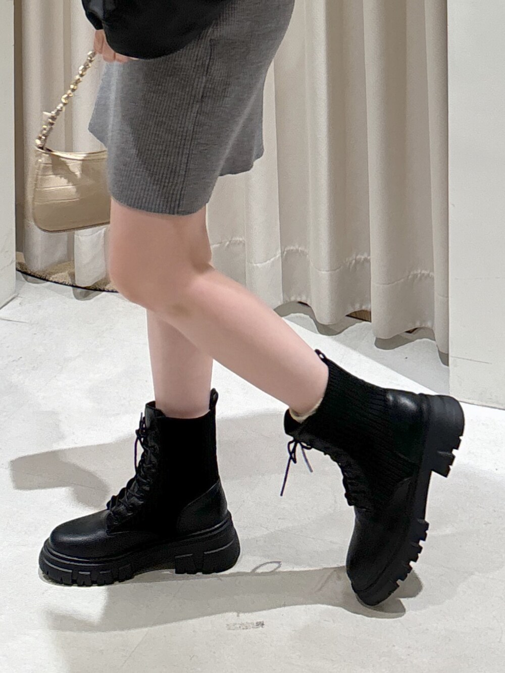 グレー系のワンピース、ベージュ系のトートバッグ、ブラック系のブーツを着用したレディースの秋コーディネートの6枚目の写真