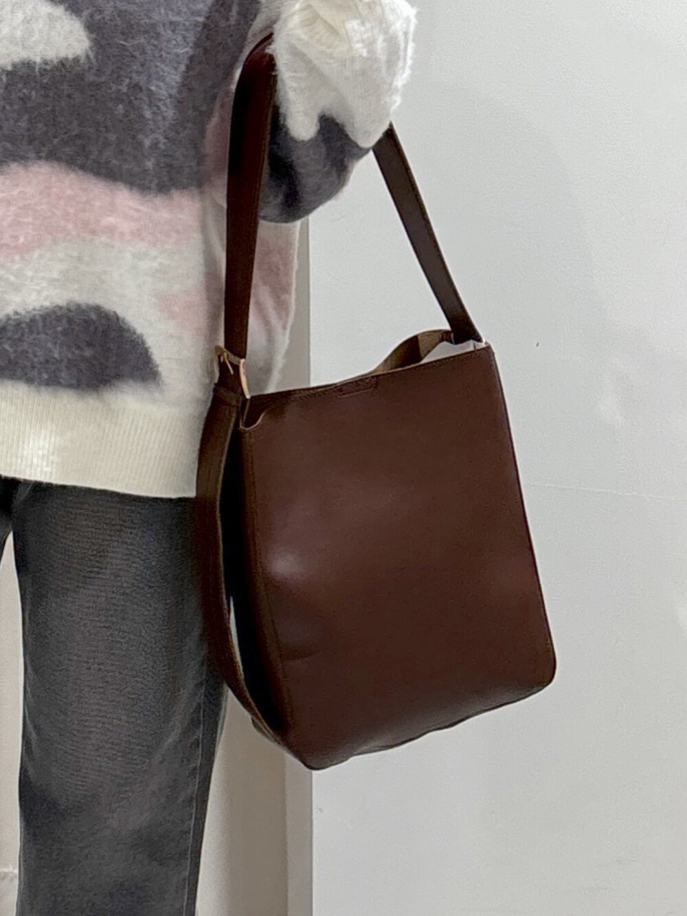 ホワイト系のニット/セーター、ブラウン系のトートバッグ、ブラック系のデニムパンツを着用したレディースの冬コーディネートの4枚目の写真