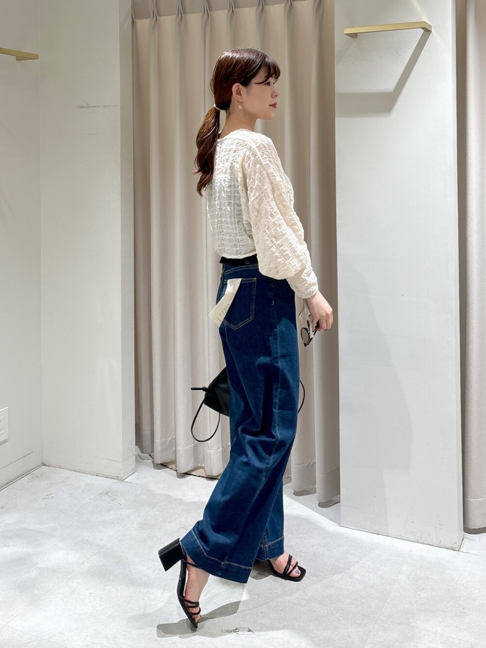 ホワイト系のカーディガン/ボレロ、ブラック系のキャミソール、ブルー系のデニムパンツを着用したレディースの夏コーディネートの4枚目の写真