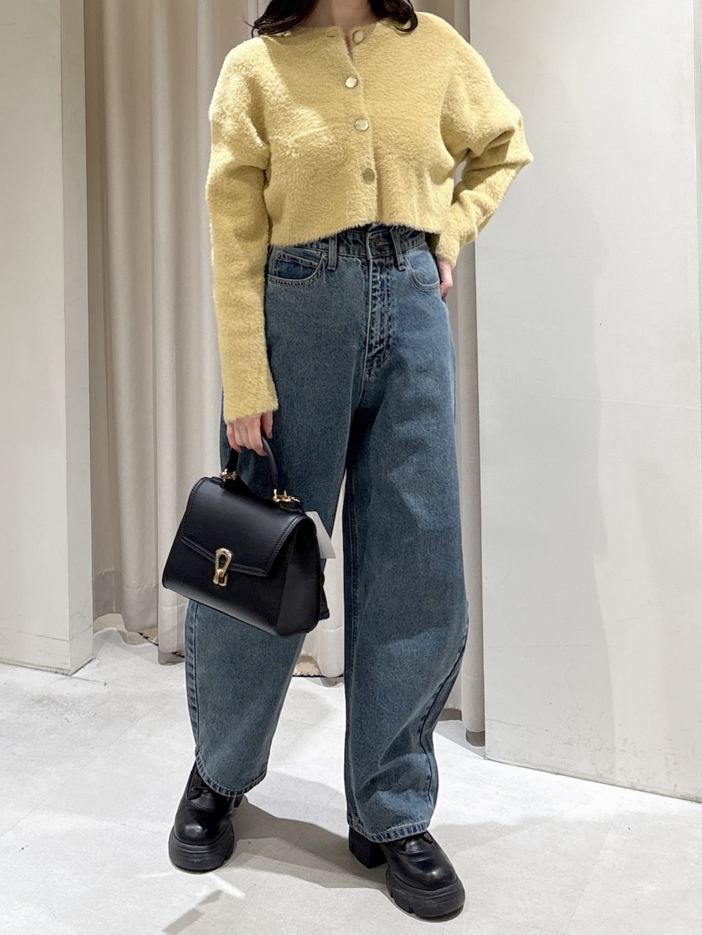イエロー系のニット/セーター、ブラック系のトートバッグ、ブルー系のデニムパンツを着用したレディースの冬コーディネートの4枚目の写真