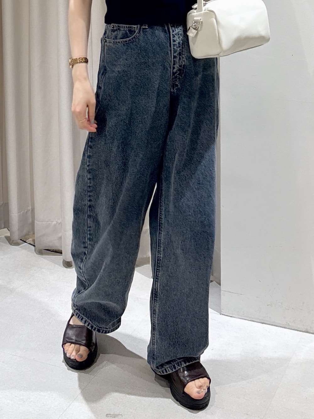 ブルー系のニット/セーター、ホワイト系のハンドバッグ、ブルー系のデニムパンツを着用したレディースの夏コーディネートの3枚目の写真
