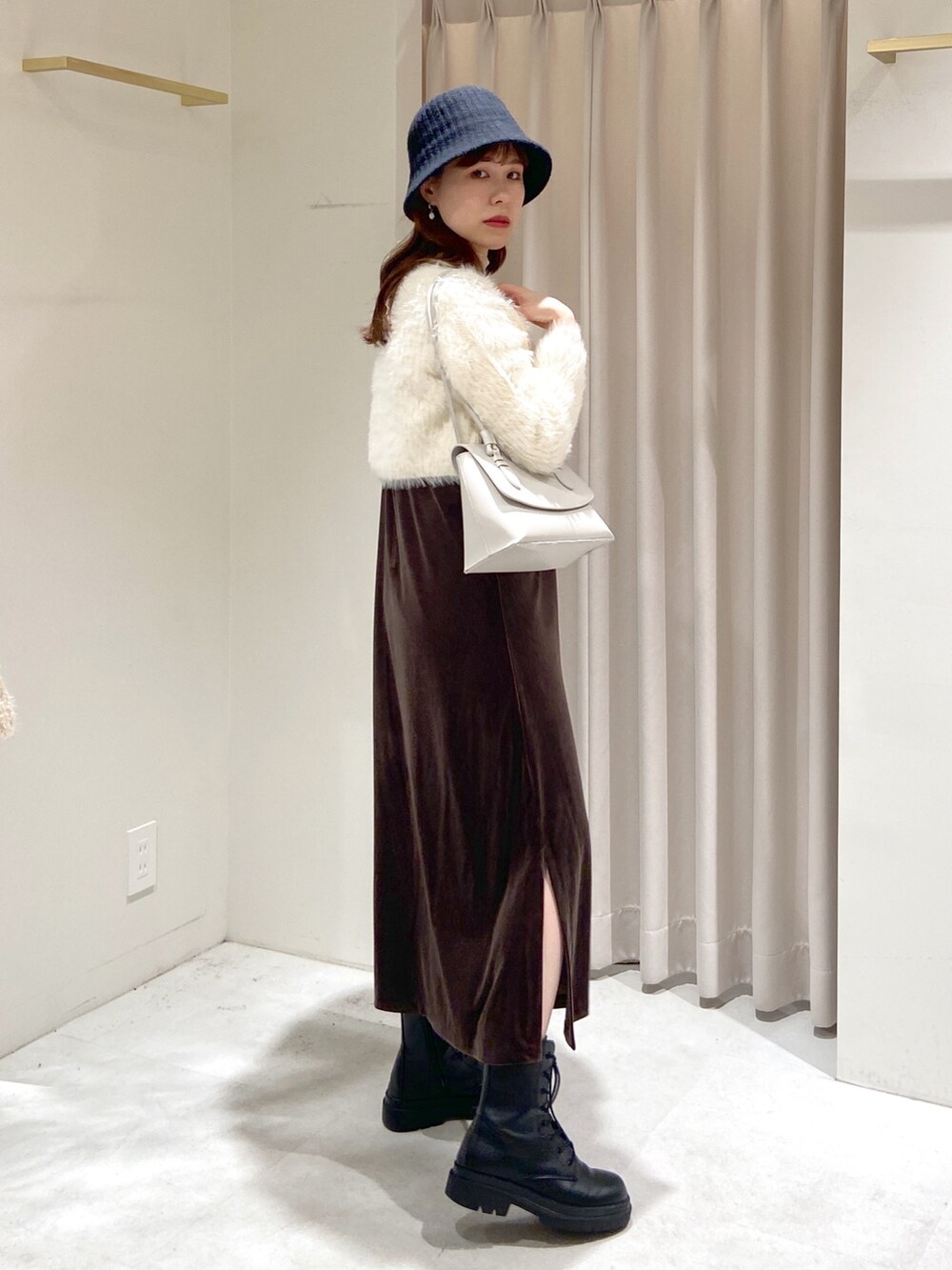 ブラウン系のワンピース、ホワイト系のショルダーバッグ、ブラック系のブーツを着用したレディースの冬コーディネートの2枚目の写真