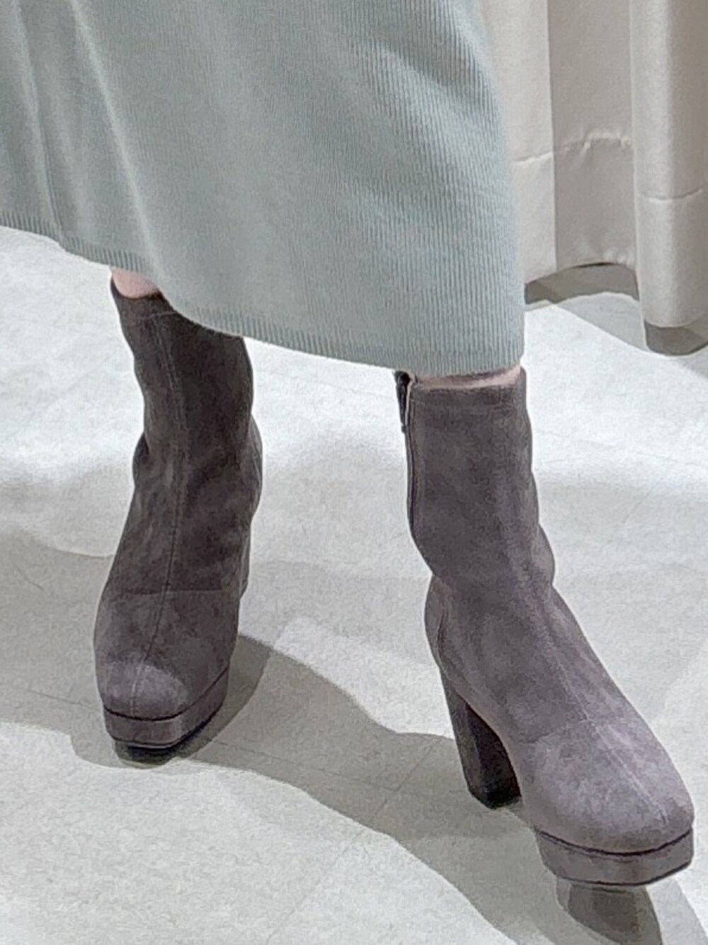 グリーン系のワンピース、ブラック系のショルダーバッグ、グレー系のブーツを着用したレディースの冬コーディネートの6枚目の写真