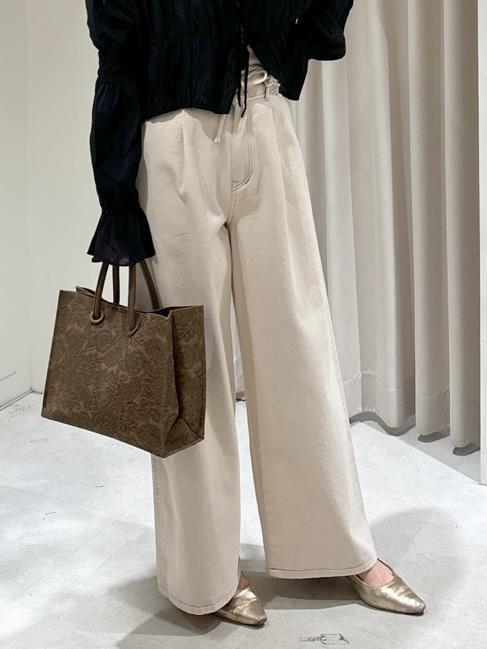 ブラウン系のトートバッグ、ホワイト系のデニムパンツ、ゴールド系のパンプスを着用したレディースの春コーディネートの3枚目の写真