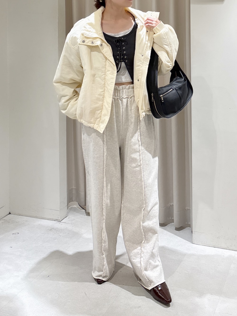 ホワイト系のブルゾン、ブラック系のハンドバッグ、ホワイト系のスウェットパンツを着用したレディースの秋コーディネートの5枚目の写真