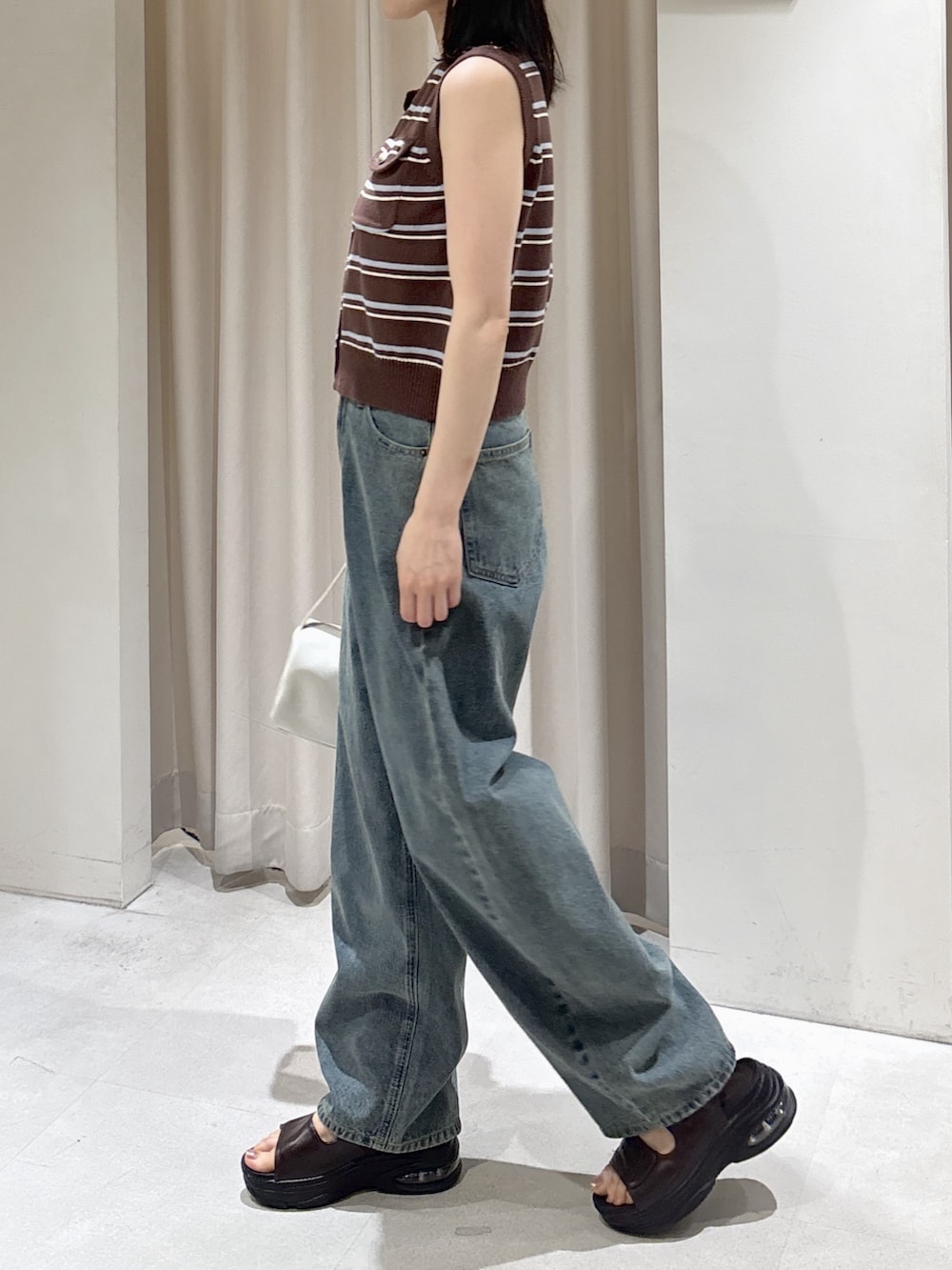 ブラウン系のニット/セーター、ブルー系のデニムパンツ、ブラウン系のサンダルを着用したレディースの夏コーディネートの2枚目の写真