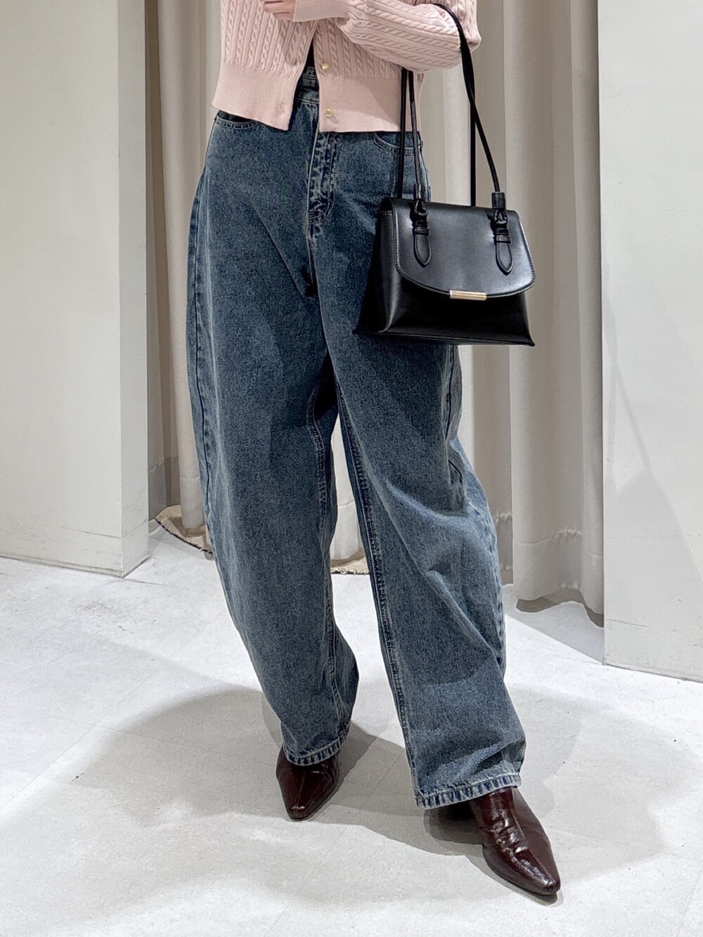 ピンク系のニット/セーター、ブラック系のショルダーバッグ、ブルー系のデニムパンツを着用したレディースの冬コーディネートの5枚目の写真