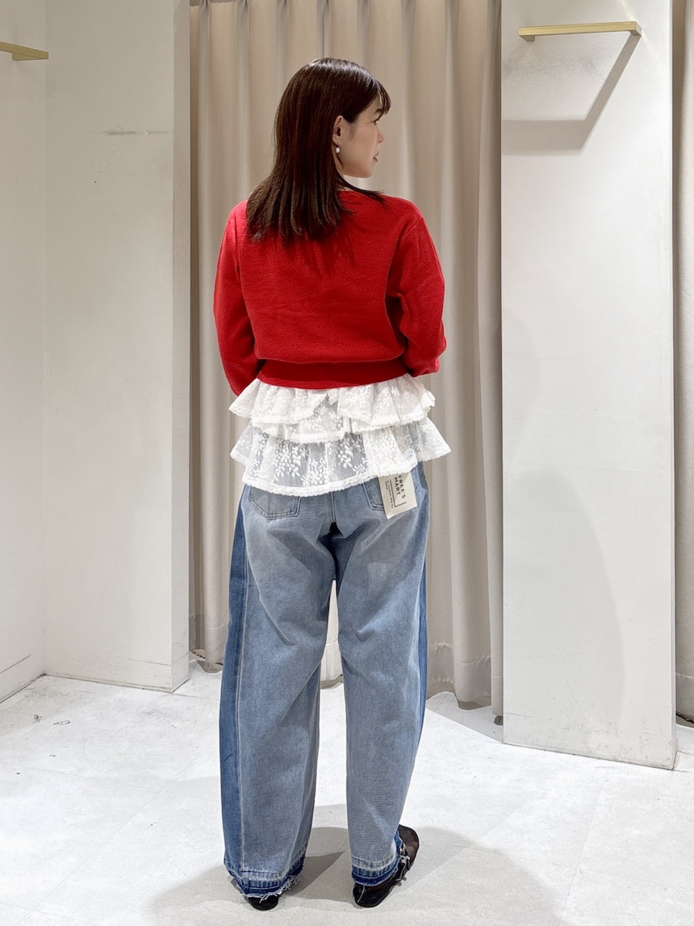 レッド系のニット/セーター、ホワイト系のシャツ/ブラウス、ブラック系のハンドバッグを着用したレディースの冬コーディネートの2枚目の写真