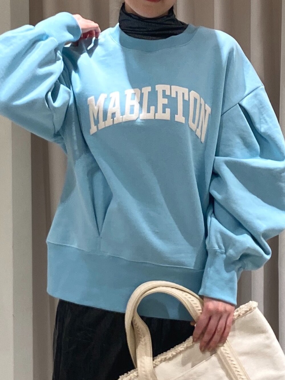 ブルー系のスウェット、ホワイト系のトートバッグ、ブラック系のスカートを着用したレディースの冬コーディネートの3枚目の写真