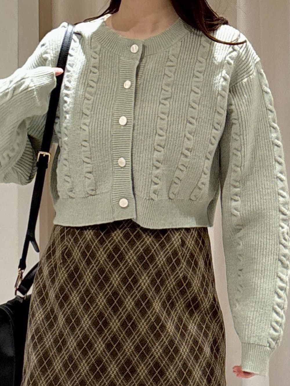 グリーン系のワンピース、ブラウン系のスカート、ブラック系のトートバッグを着用したレディースの冬コーディネートの3枚目の写真