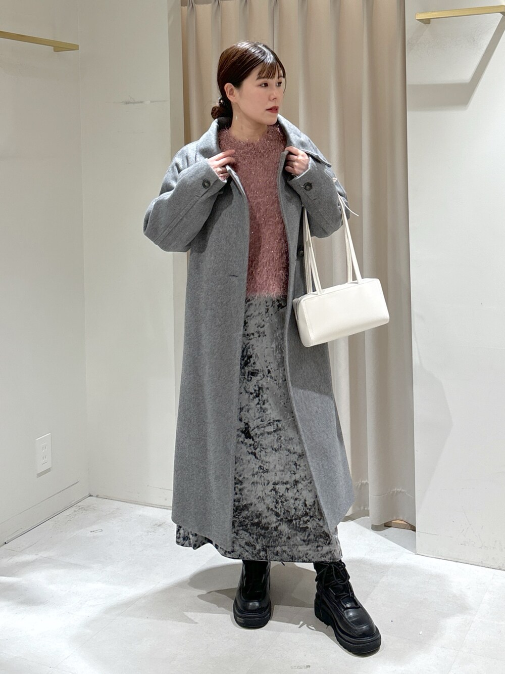 グレー系のステンカラーコート、ホワイト系のショルダーバッグ、ブラック系のブーツを着用したレディースの冬コーディネートの4枚目の写真