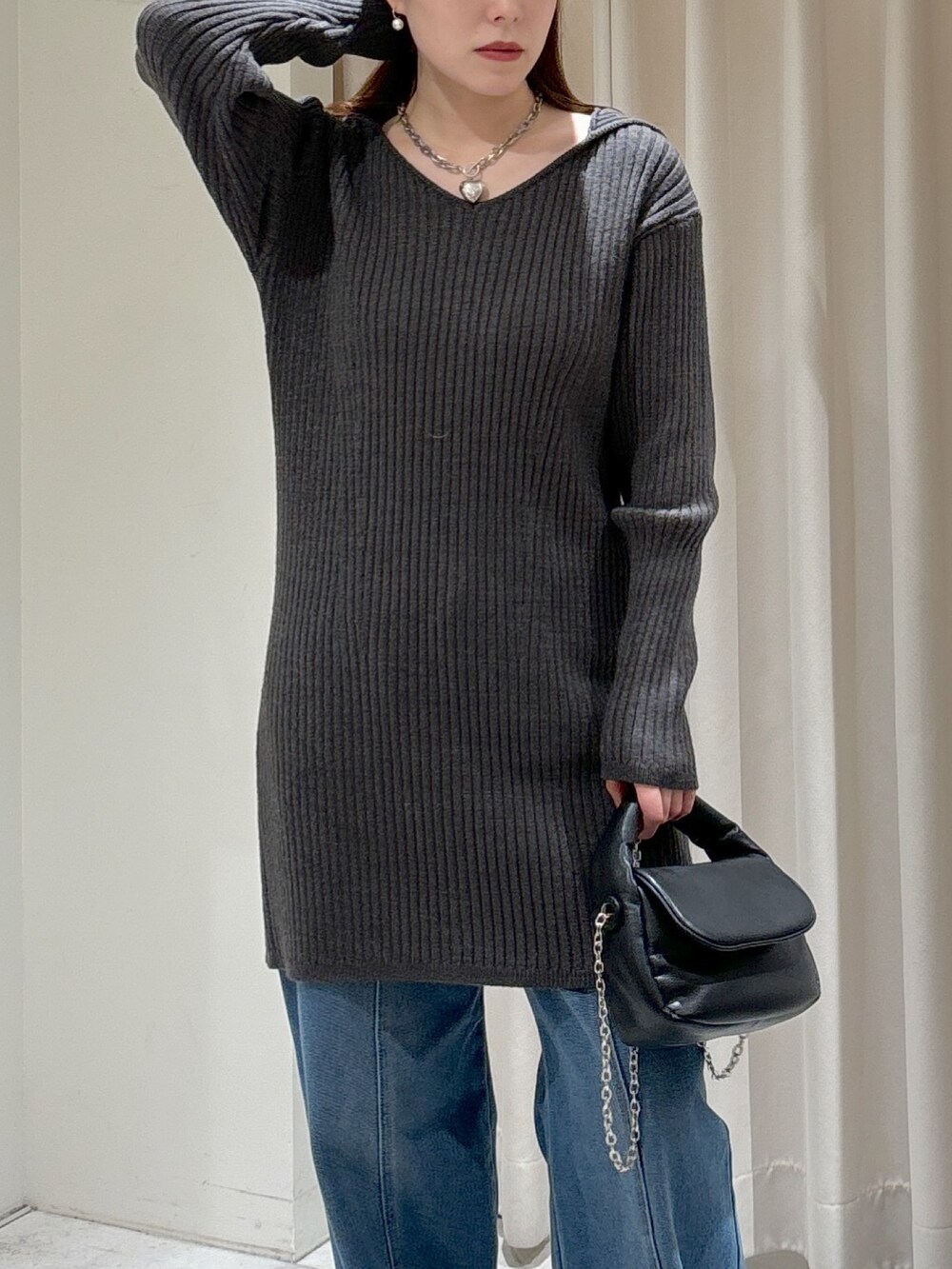 グレー系のワンピース、ブラック系のショルダーバッグ、ブルー系のデニムパンツを着用したレディースの冬コーディネートの4枚目の写真