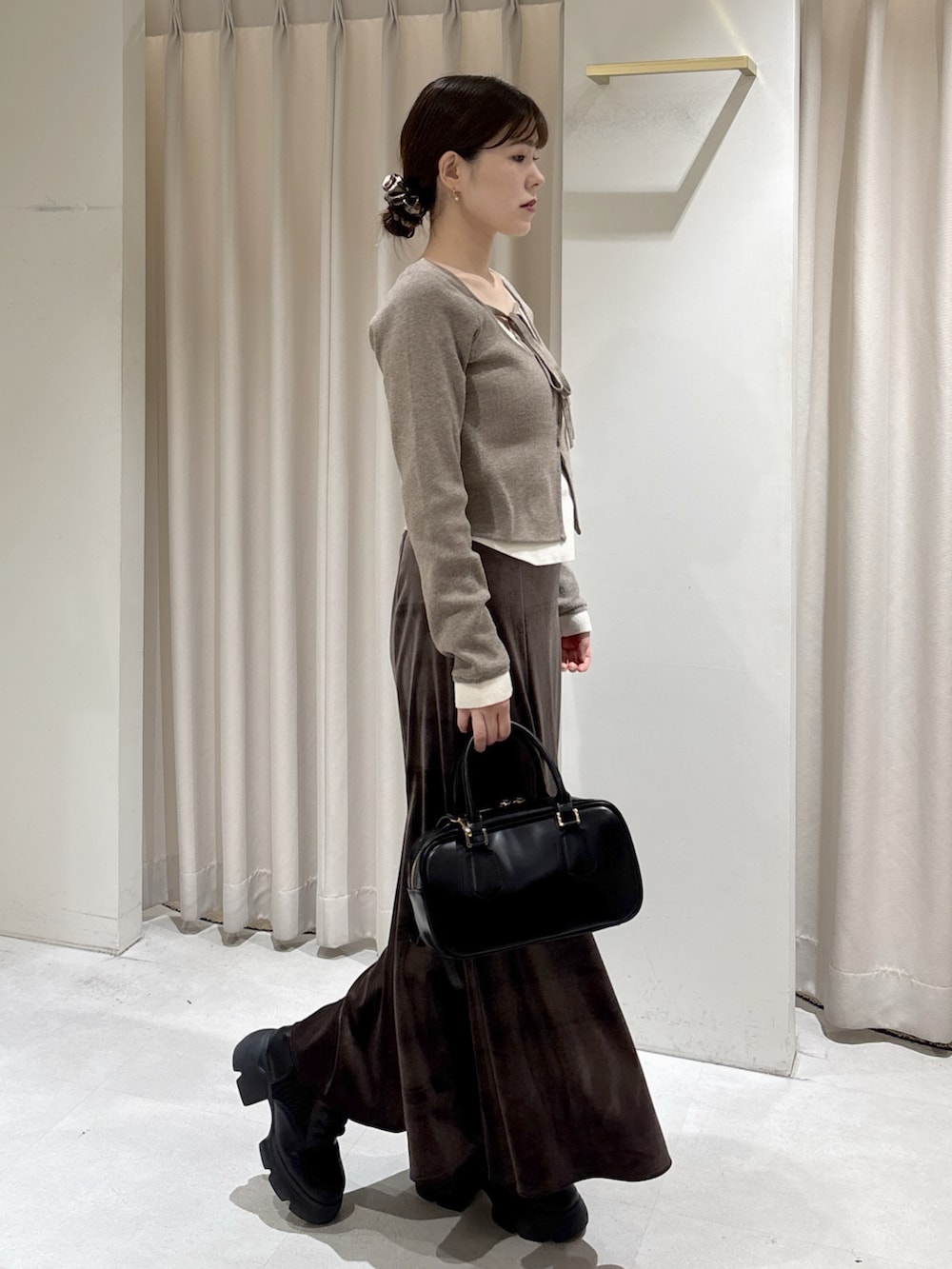 ブラウン系のニット/セーター、ブラウン系のスカート、ブラック系のブーツを着用したレディースの冬コーディネートの2枚目の写真