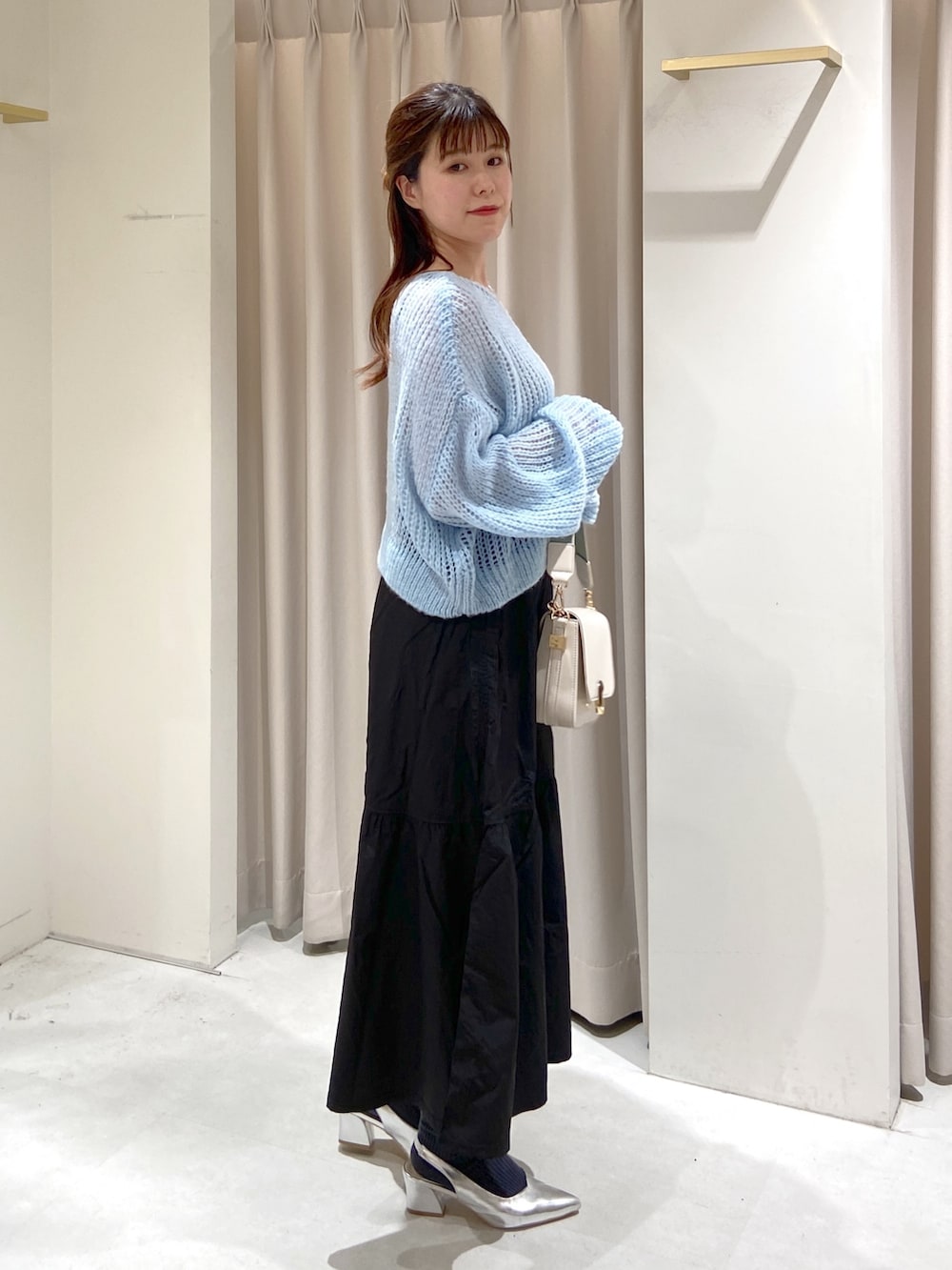 ブルー系のニット/セーター、ホワイト系のショルダーバッグ、ブラック系のスカートを着用したレディースの冬コーディネートの3枚目の写真