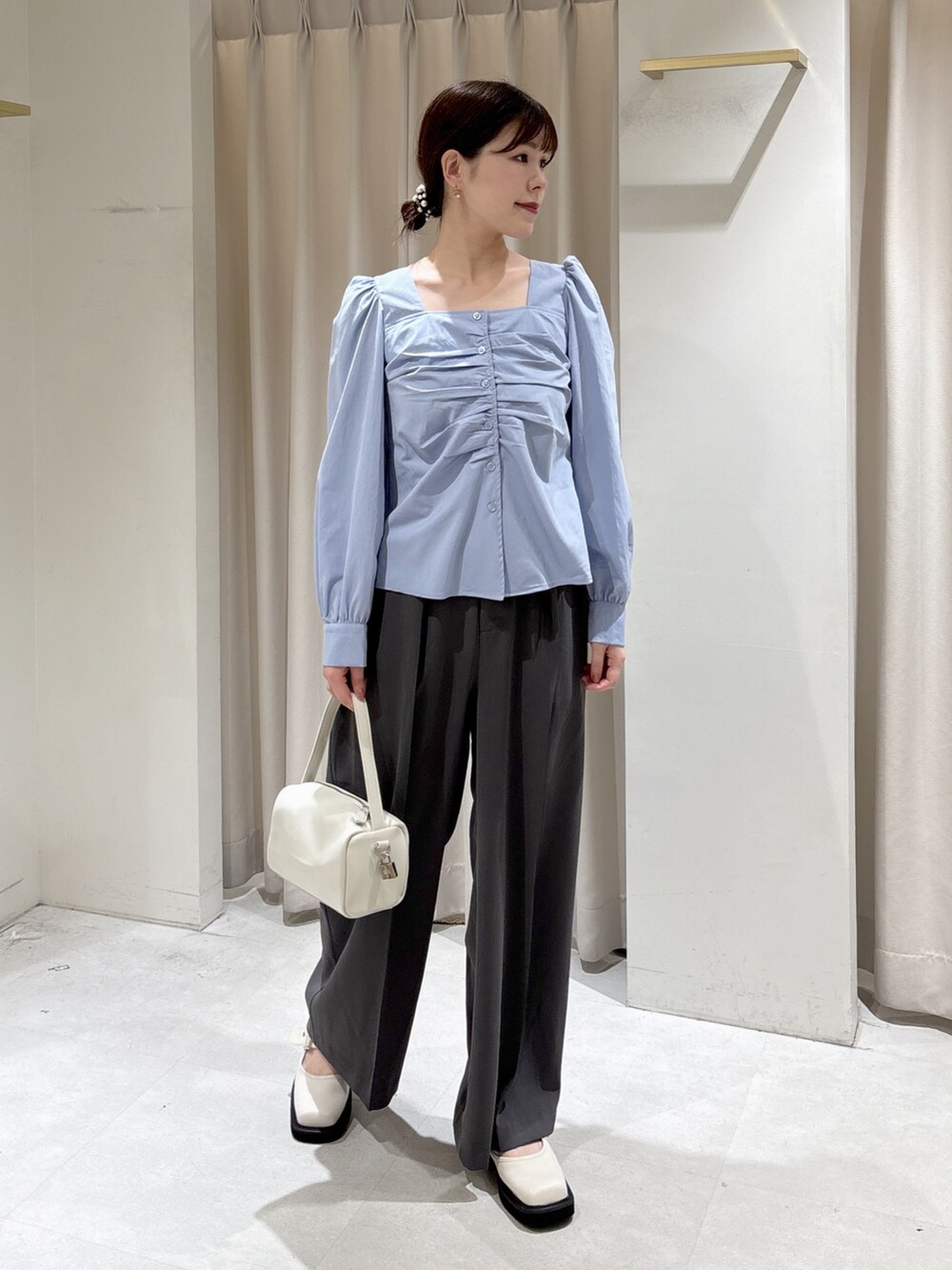 ブルー系のシャツ/ブラウス、グレー系のスラックス、ホワイト系のハンドバッグを着用したレディースの冬コーディネートの4枚目の写真